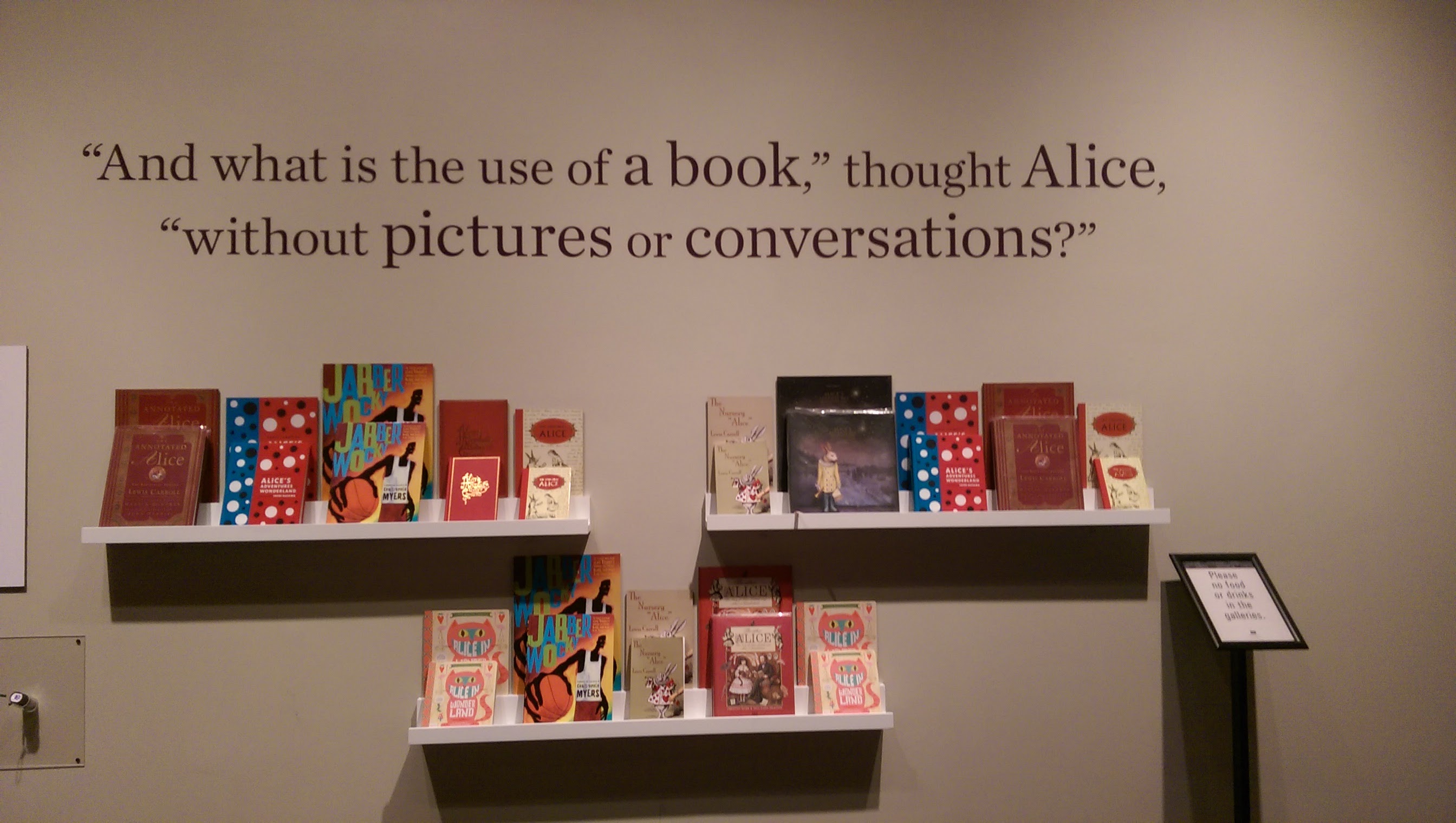 2015-02-25 13.36.39 quote "Whatsi s the use of a book," thought Alice, "without pictures or conversations?" with multiple editions of Alice in Wonderland on shelves below the quote